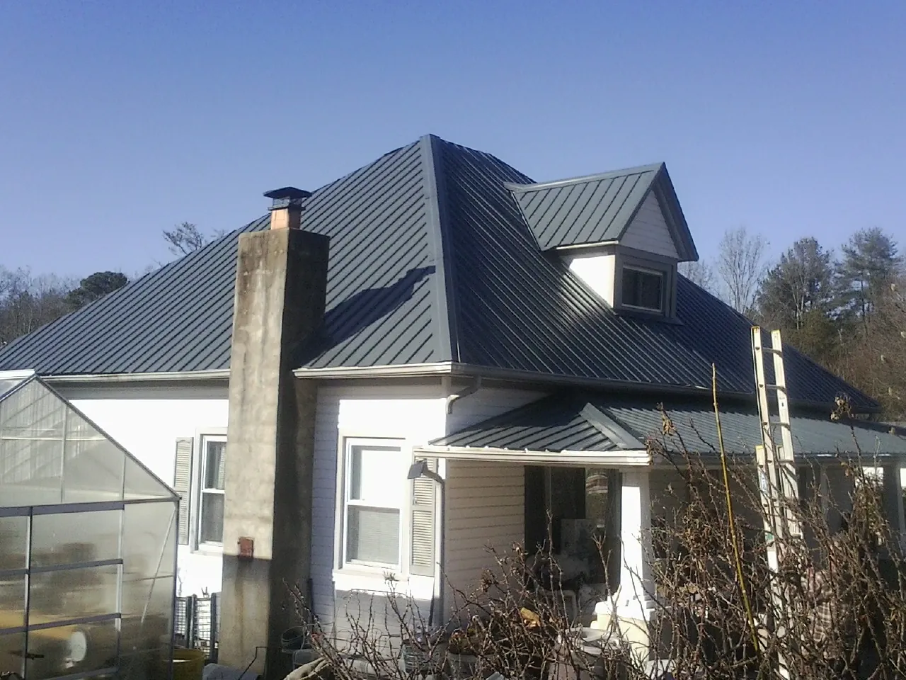 Dark blue standing seam metal roof on a white farmhouse with dormer — Slate & Tile Roof Repair by Roofing Brothers in Wellersburg
