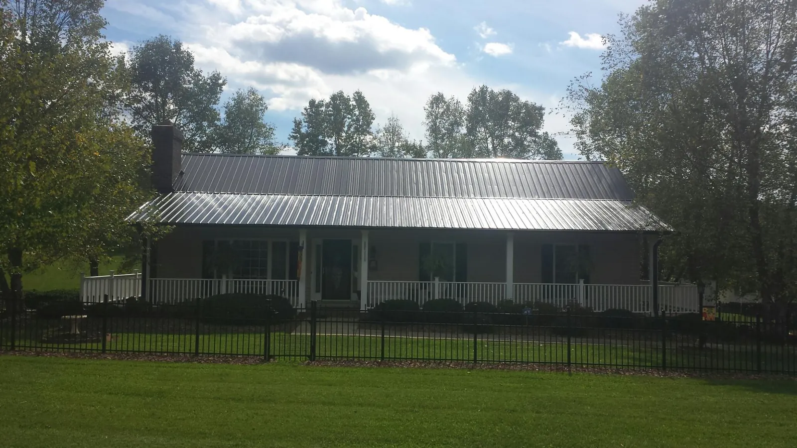 Gray metal roof on a brick ranch with a full width front porch — Gutter Guard Installation work by our crew in Wellersburg