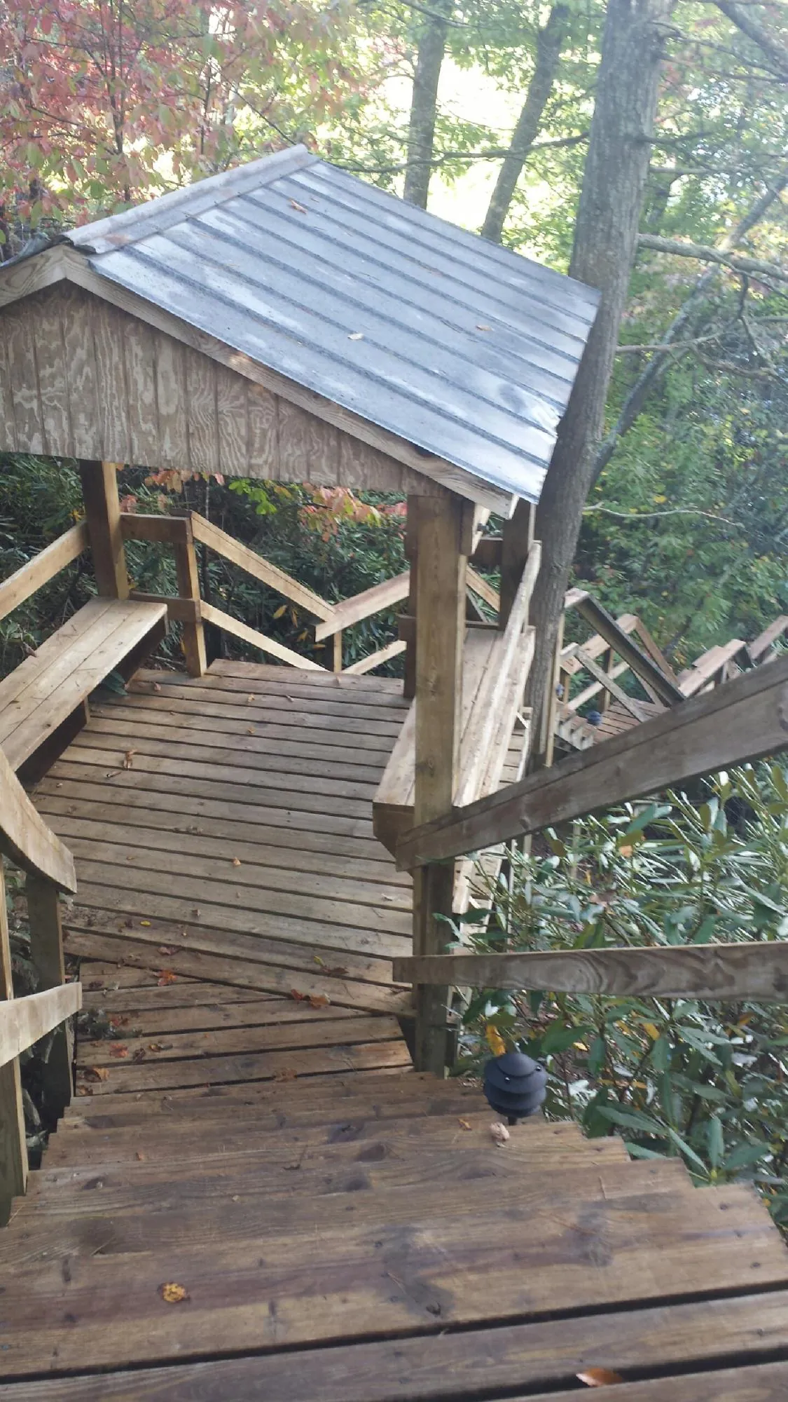 Metal roofed shelter over wooden steps on a wooded walkway — Skylight Repair & Installation work by our crew in Wellersburg