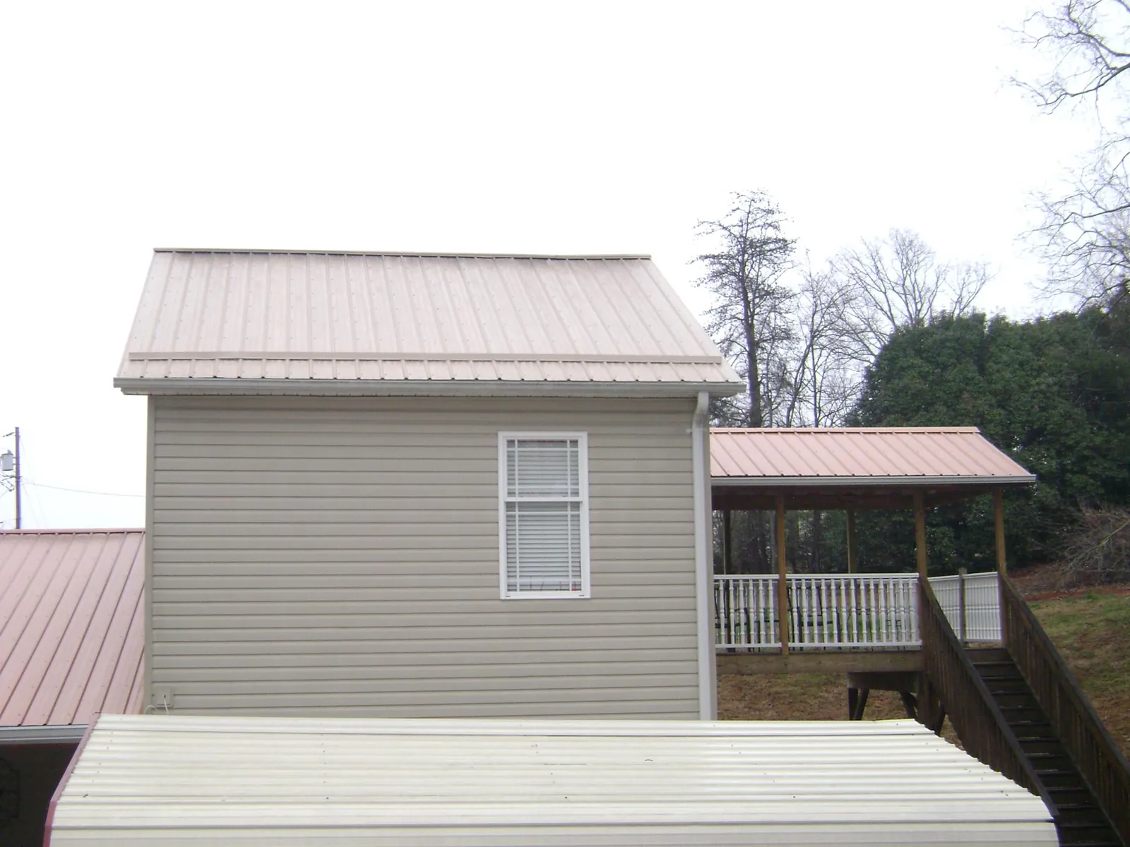 Tan metal roofs on a two story addition and attached porch, from a Roof Replacement job in Wellersburg