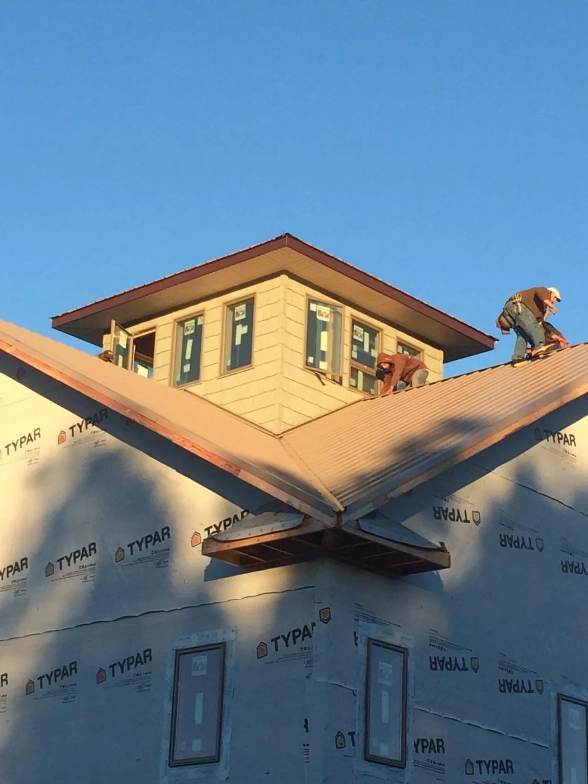 Roofers working around a rooftop cupola on a new metal roof at sunset — Roof Waterproofing in Wellersburg by Roofing Brothers